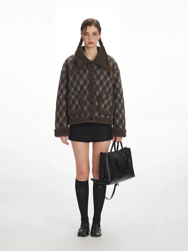 Woman wearing a brown plaid bomber jacket with shearling trim and a black mini skirt.