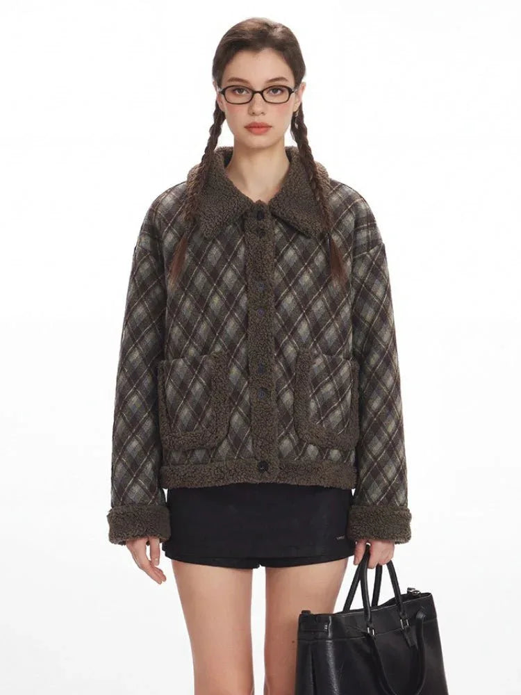 Front view of a woman with glasses wearing a collared plaid bomber jacket and black shorts.