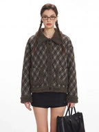 Front view of a woman with glasses wearing a collared plaid bomber jacket and black shorts.
