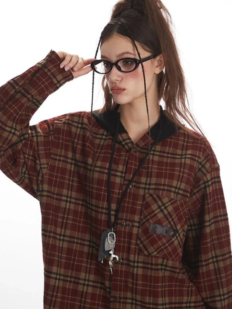Close-up of a woman wearing a red and tan plaid hooded flannel shirt and oval-shaped glasses.