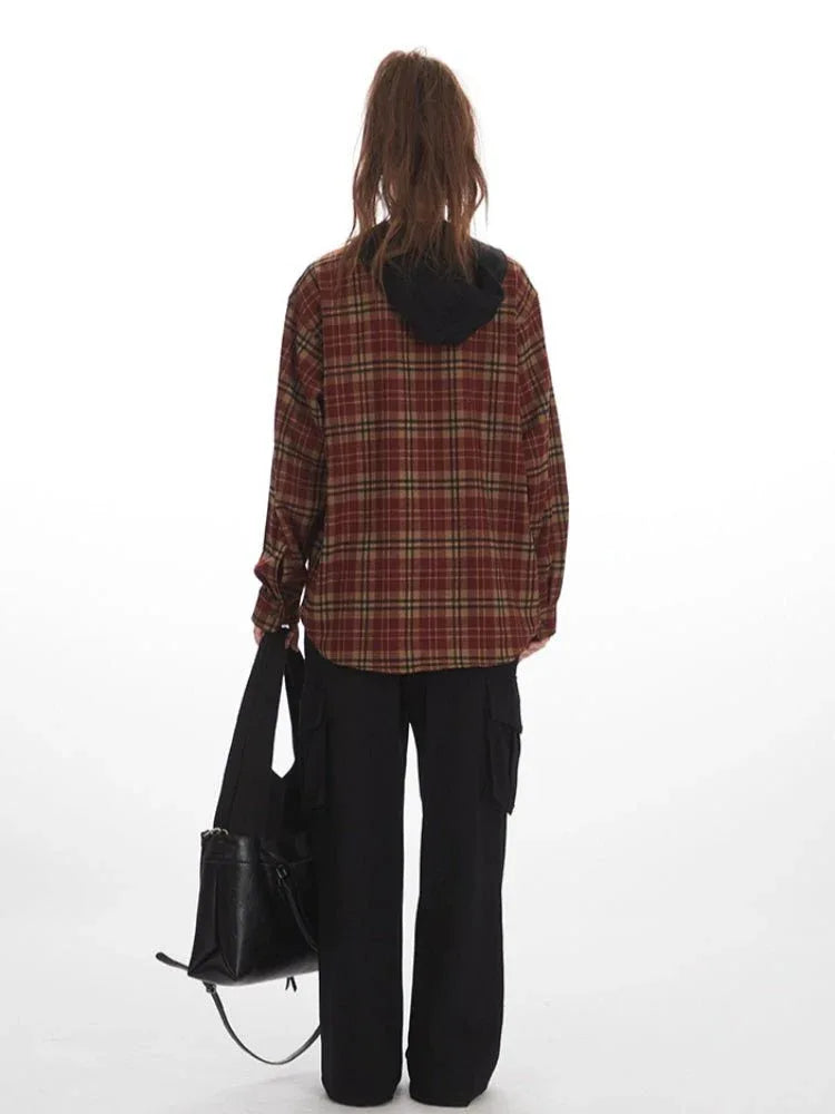 Woman wearing a red and tan plaid hooded flannel shirt with black cargo pants and a black handbag.