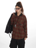 Close-up of a woman wearing a red and tan plaid hooded flannel shirt, holding a black handbag over her shoulder.