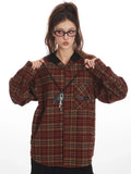 Woman adjusting the collar of her red and tan plaid hooded flannel shirt.