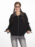 Front view of a woman in a black bomber jacket, showcasing the zip closure and logo patch.