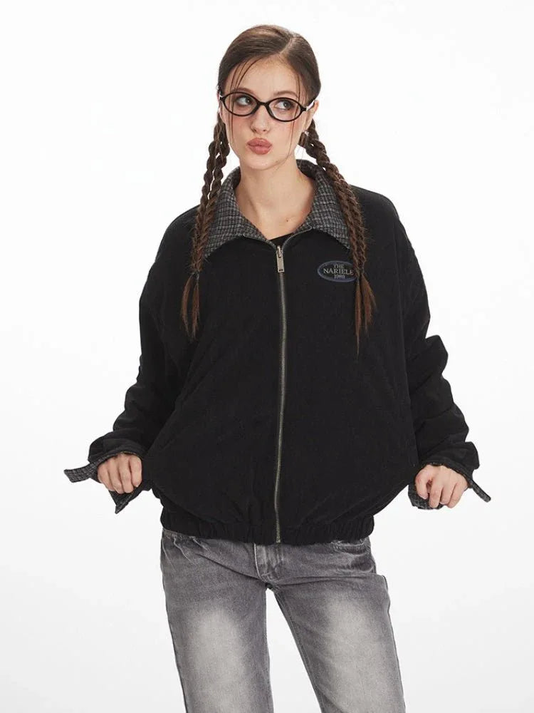 Front view of a woman in a black bomber jacket, showcasing the zip closure and logo patch.
