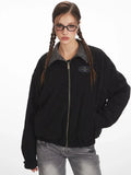 Close-up of a woman wearing a black bomber jacket with a grey plaid collar.