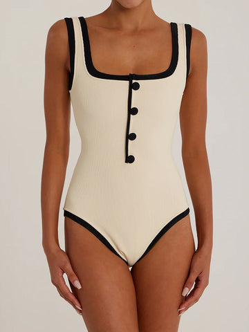 Woman wearing a cream ribbed knit one-piece swimsuit with black trim and four black buttons down the front.
