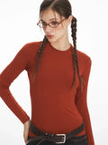 Detailed view of a model's face and upper torso, showcasing the rust-colored long-sleeve top and neckline.