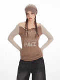 Woman in a brown long-sleeve graphic t-shirt with beige sleeves, dark wash wide-leg jeans, and a brown beret, posing with hands on hips.