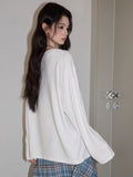 Side view of a model wearing a white long sleeve t-shirt with a graphic print.
