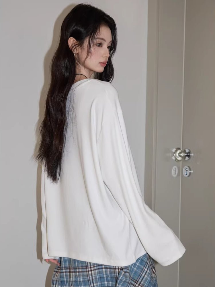 Side view of a model wearing a white long sleeve t-shirt with a graphic print.