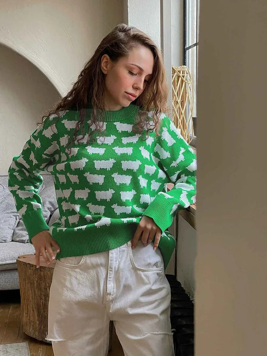 Woman wearing a green sweater with a white sheep pattern and white pants