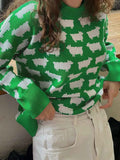 Woman wearing a green sweater with a white sheep pattern