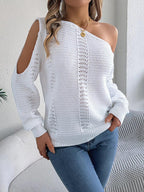 Woman posing with hands at her waist, wearing a white off-the-shoulder knit sweater and blue jeans