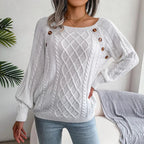 Full-body shot of a woman modeling a white cable knit sweater with a boat neck and button embellishments.