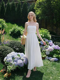 Woman wearing a white strapless ruched waist maxi dress walking in a garden
