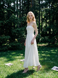 Woman wearing a white strapless ruched waist maxi dress standing in a forest