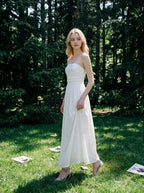 Woman wearing a white strapless ruched waist maxi dress standing in a forest
