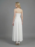 Woman wearing a white strapless ruched waist maxi dress, back view
