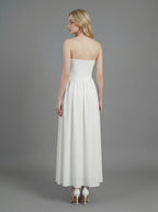 Woman wearing a white strapless ruched waist maxi dress, back view