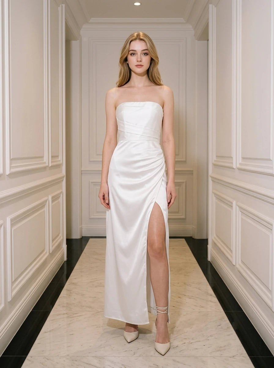 Woman wearing a white strapless satin gown with a high slit standing in a hallway