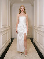 Woman wearing a white strapless satin gown with a high slit standing in a hallway