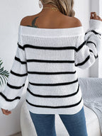 Back view of a woman wearing a white and black striped off-the-shoulder knit sweater with blue jeans