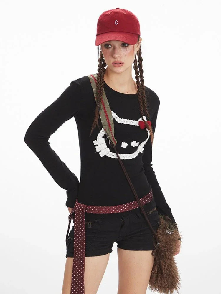 Close-up of a woman wearing a black long-sleeved shirt with a white cat graphic print and a red bow detail.