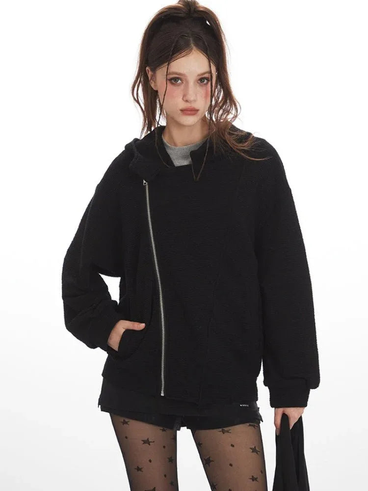 Close-up of a woman wearing a black textured fleece hoodie with an asymmetrical zipper and front pocket.