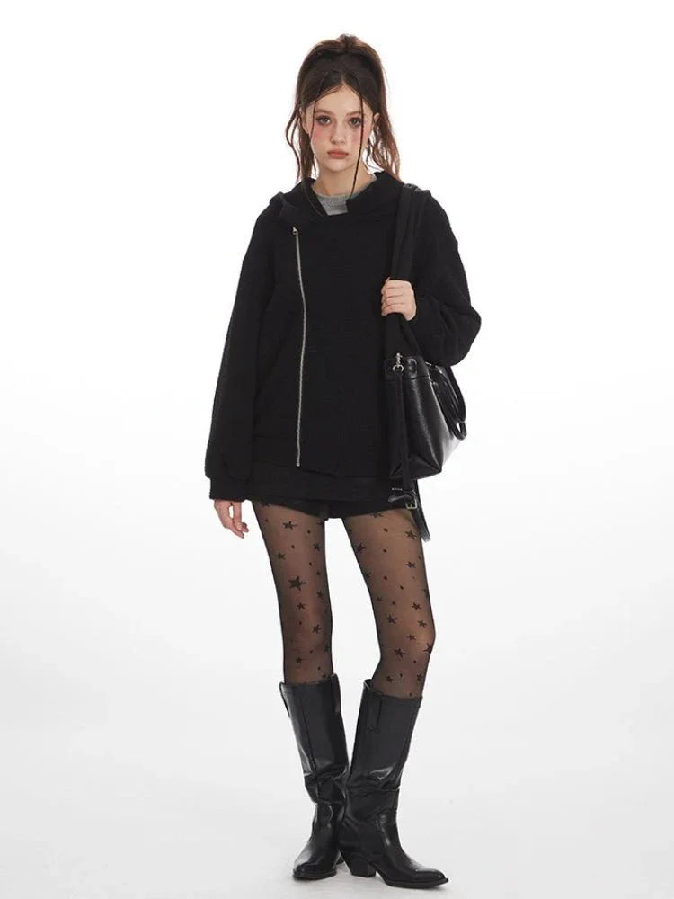 Front view of a woman wearing a black textured fleece hoodie with an asymmetrical zipper, layered over a grey t-shirt.