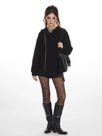 Front view of a woman wearing a black textured fleece hoodie with an asymmetrical zipper, layered over a grey t-shirt.