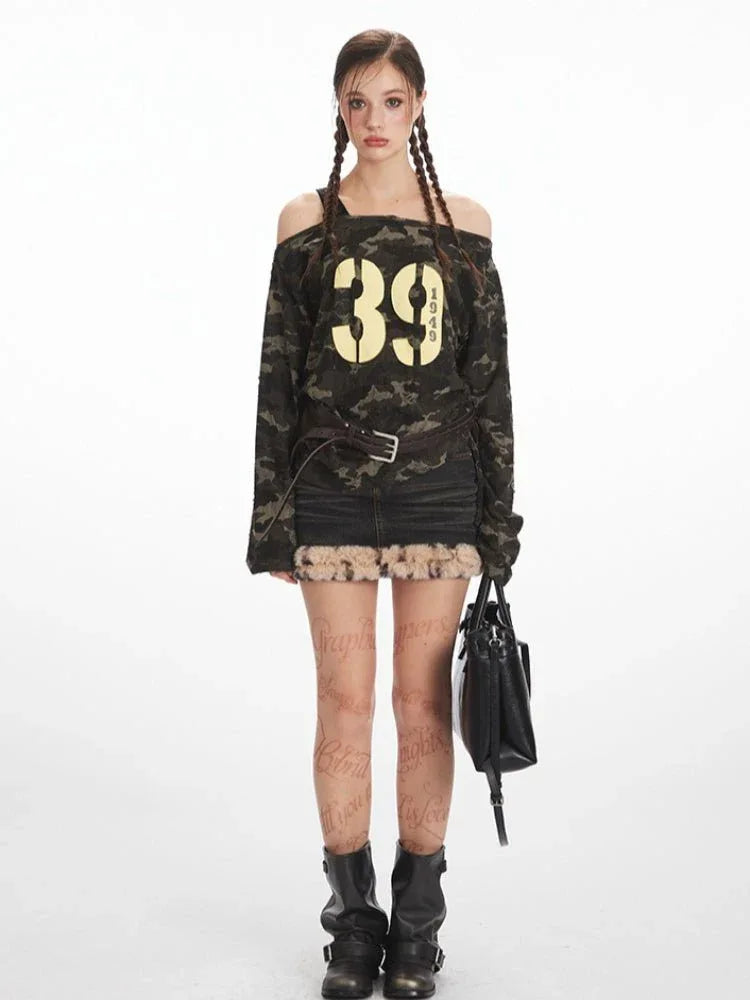 Woman wearing a camouflage print off-shoulder long sleeve top with a "39 1949" graphic print, paired with a denim skirt and boots.