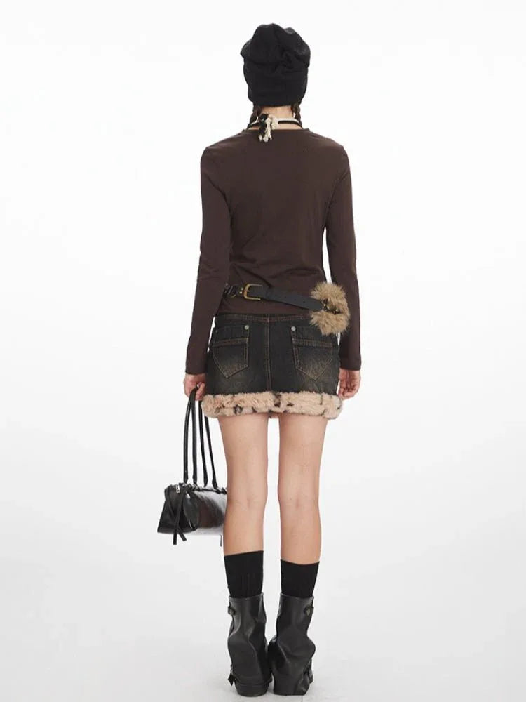Back view of a model in a brown long-sleeved top and a faux fur-trimmed denim mini skirt.