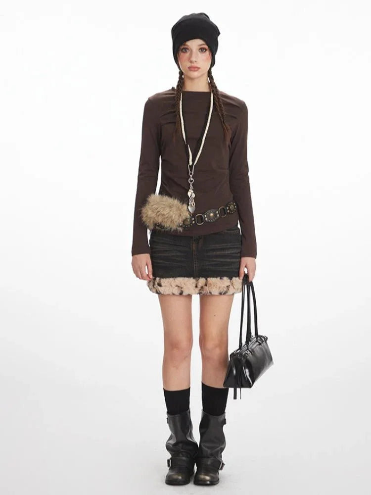 Model wearing a long-sleeved brown top and a distressed denim mini skirt with faux fur trim.
