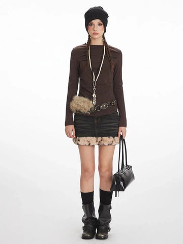 Model wearing a long-sleeved brown top and a distressed denim mini skirt with faux fur trim.