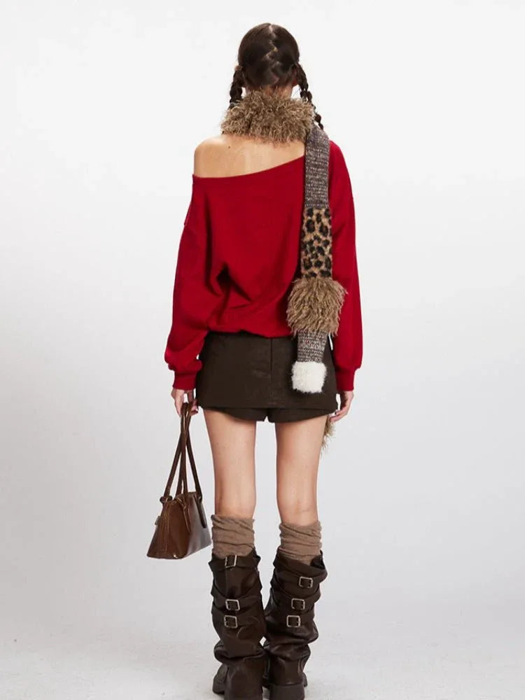 Back view of a woman wearing a red off-the-shoulder sweatshirt with a Hello Kitty graphic, brown mini skirt, brown knee-high boots, and a leopard print scarf.