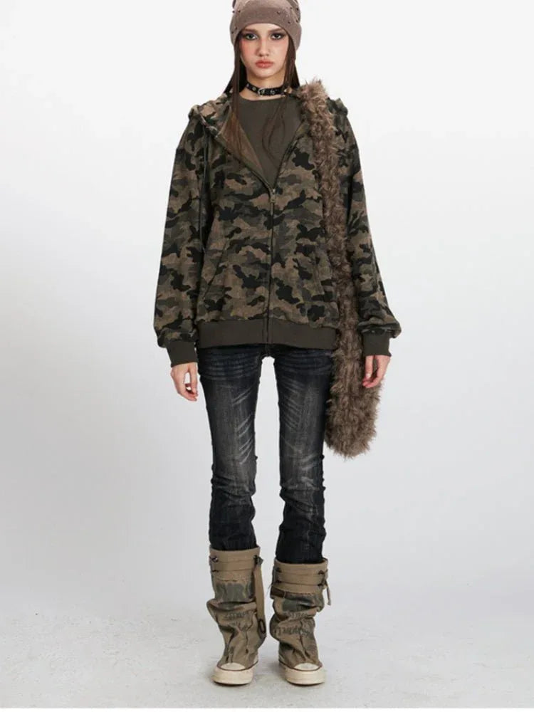 Woman wearing a camouflage print hooded zip-up jacket with a beanie and dark wash jeans Main image