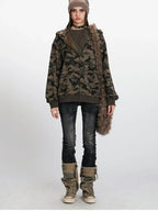 Woman wearing a camouflage print hooded zip-up jacket with a beanie and dark wash jeans