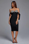 Full-length view of a woman in a black embellished midi dress with off-the-shoulder sleeves.