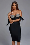 Woman wearing a black bodycon midi dress with a sweetheart neckline, pearl shoulder straps, and decorative bows on the sleeves.