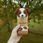 A hand holding a single white and brown knitted dog sock with a "Dog Socks" tag